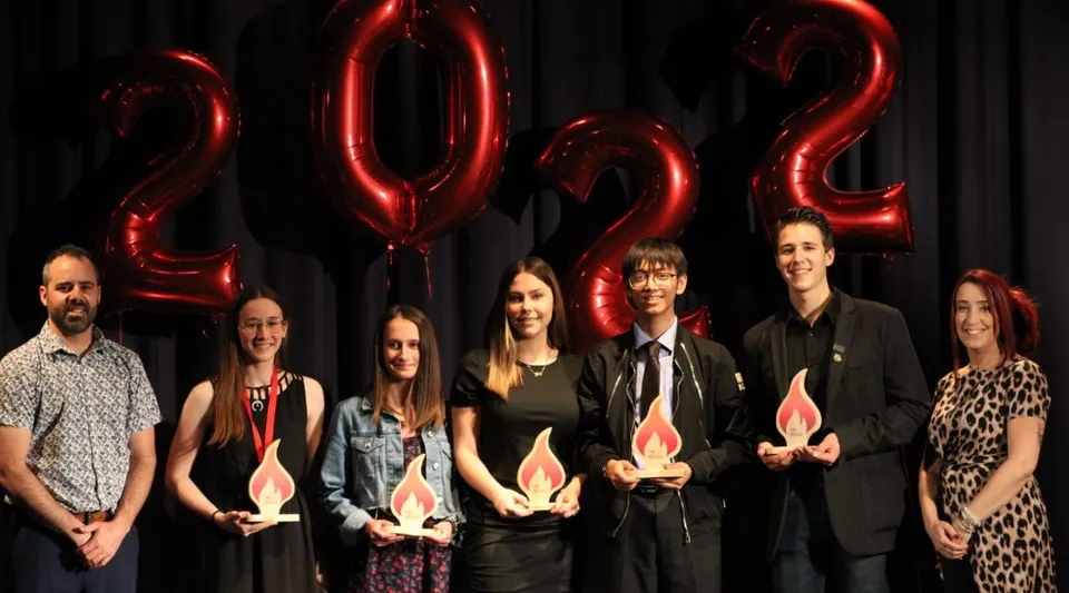 Un gruppo di studenti posa davanti a grandi palloncini rossi del 2022 nel campus della Polyvalente Alexandre-J.-Savoie.