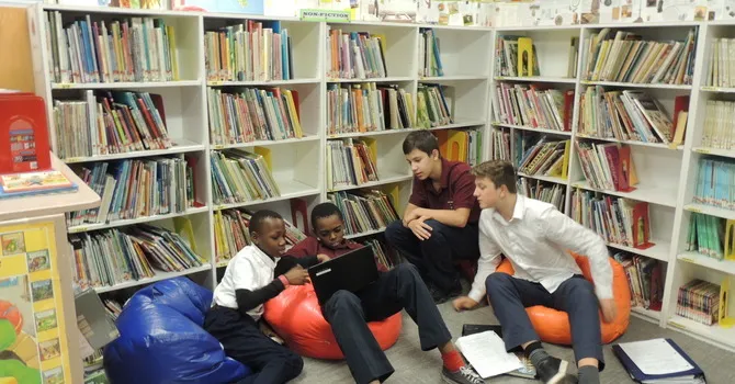 Estudiantes de la Abbotsford Christian School están sentados en pufs de colores en la biblioteca entre estanterías llenas de libros.