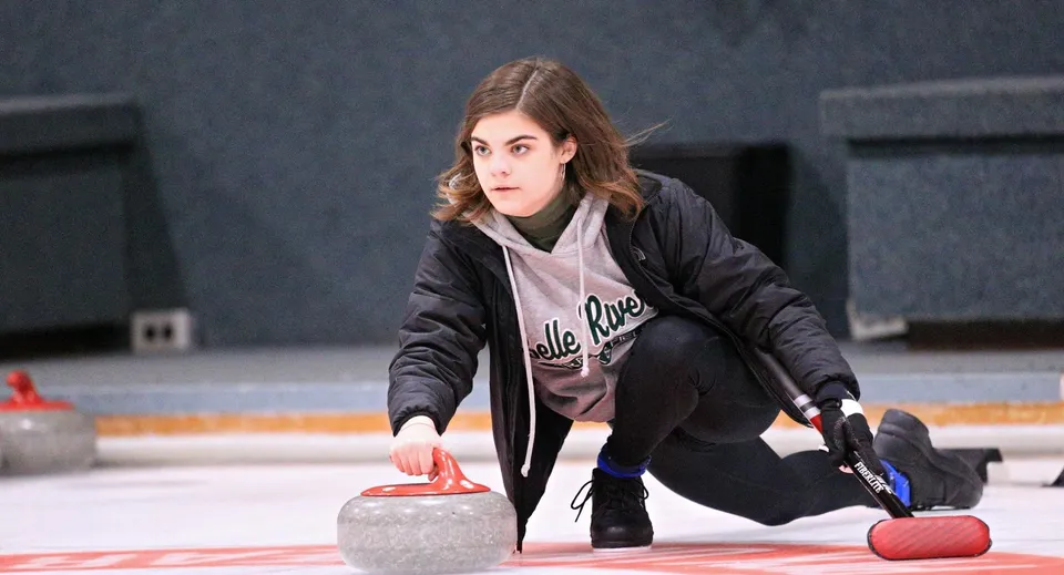Una studentessa della Belle River District High School gioca a curling su una pista di ghiaccio.