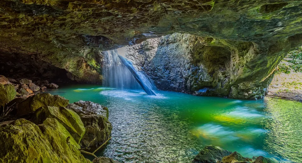 Una cascata turchese scorre su rocce coperte di muschio in un tranquillo laghetto nel terreno della Nerang State High School.