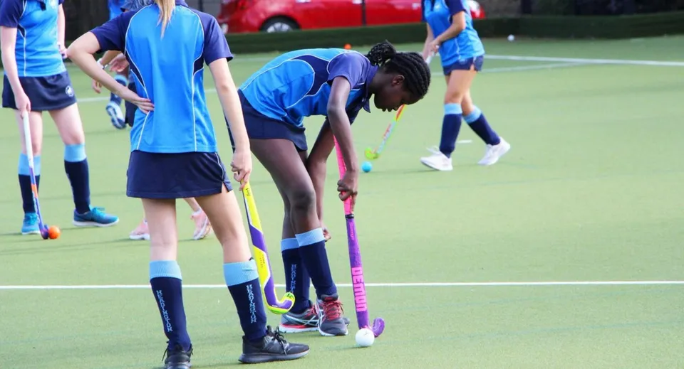 Un gruppo di giovani atlete gioca a hockey sul campo sintetico durante l'ora di educazione fisica alla Headington School.