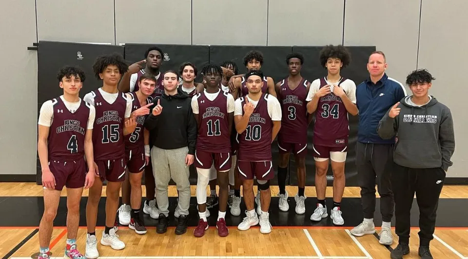 Un gruppo di giovani studenti e studentesse di pallacanestro in maglia si trova sul campo da basket della Dr. Frank J. Hayden Secondary School.