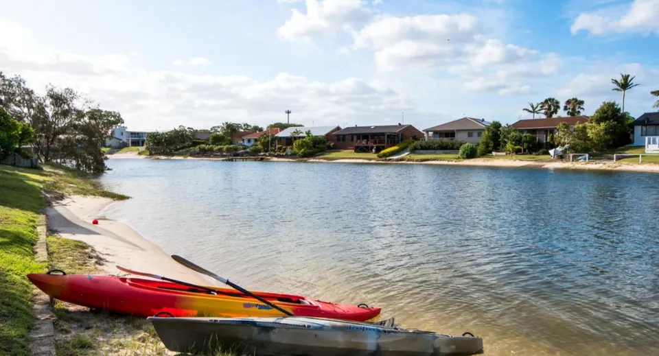 Un kayak rosso si trova su un lago calmo immerso nel verde nei pressi della Merrimac State High School.