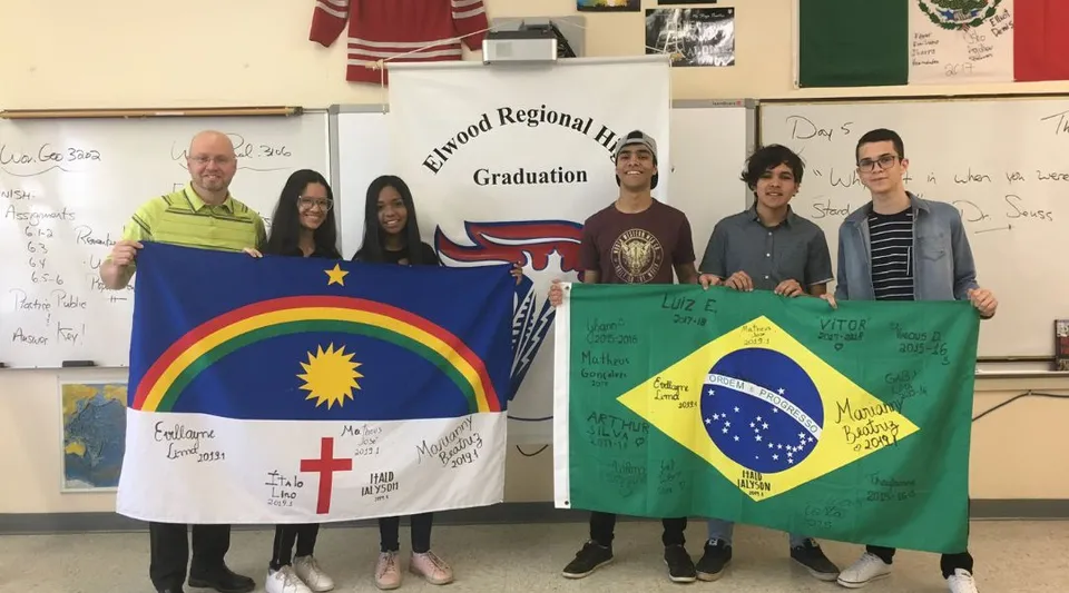 Un insegnante e studenti della Elwood Regional High posano in un'aula con due bandiere brasiliane firmate.