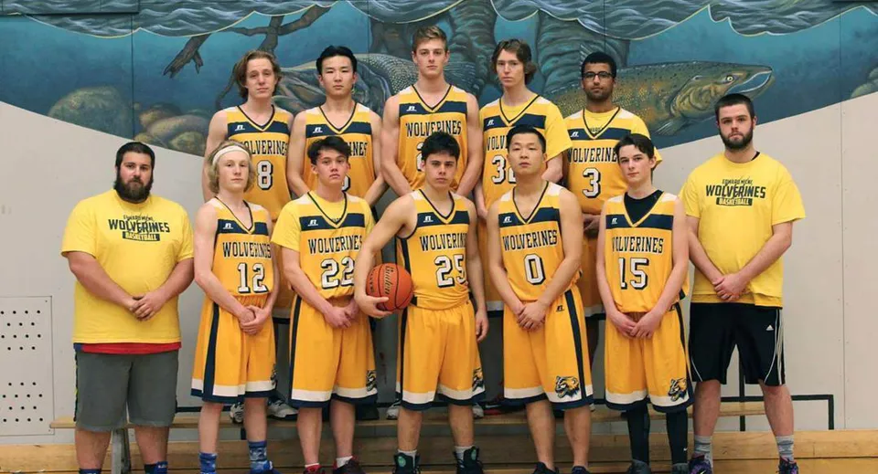 Un gruppo di studenti della Edward Milne Community School con la maglia da basket gialla posa davanti a un murale con motivo subacqueo.