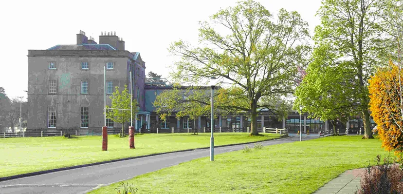 Un parco verde con alberi e un edificio storico sullo sfondo nel campus della Newtown School.