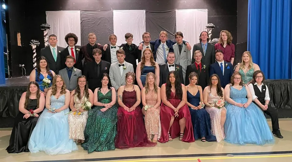 Un grande gruppo di studenti della Templeton Academy si trova su un palco davanti a uno sfondo nero e tende blu.