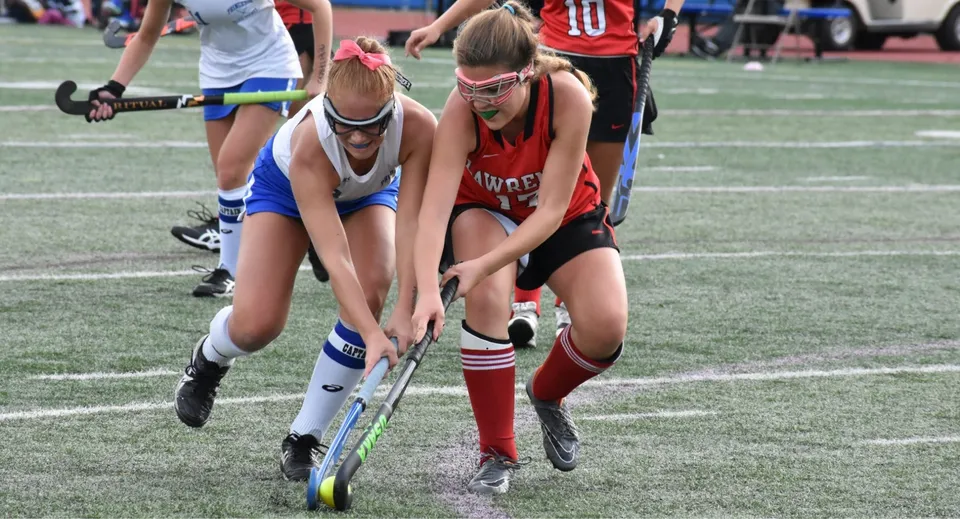 Due studentesse della Royal High School giocano una partita di hockey su prato e lottano per il possesso palla.