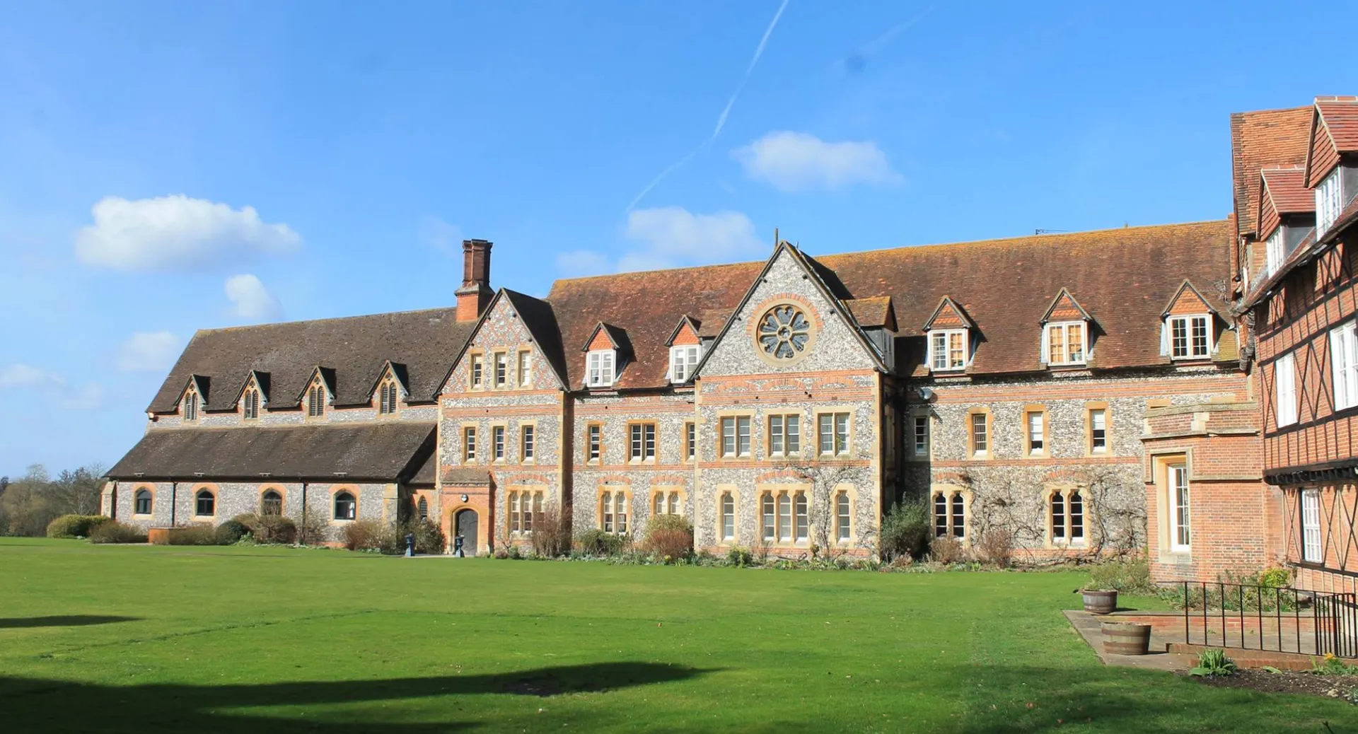 L'edificio storico in mattoni del Bradfield College si erge su un prato curato sotto un cielo blu.