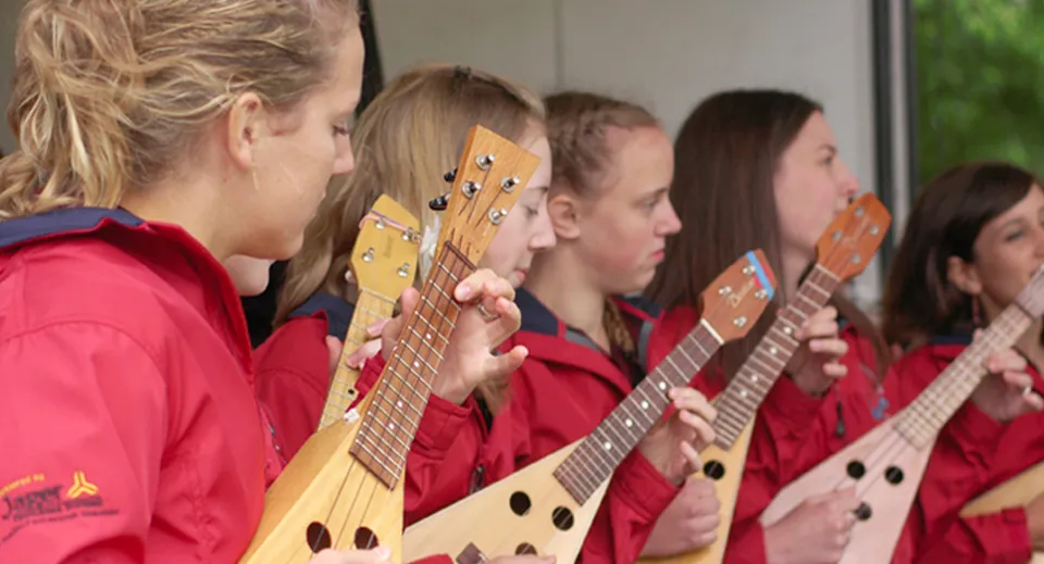 Un gruppo di studenti della Langley Fine Arts School in divisa rossa e con diverse chitarre in una sala prove.