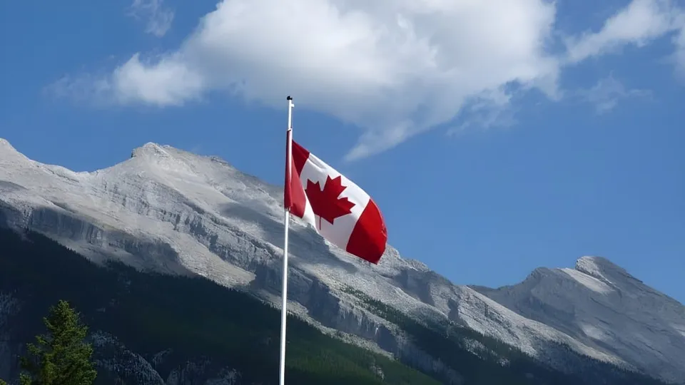 Una bandiera canadese sventola davanti a montagne innevate sul terreno della École L’Odyssée.