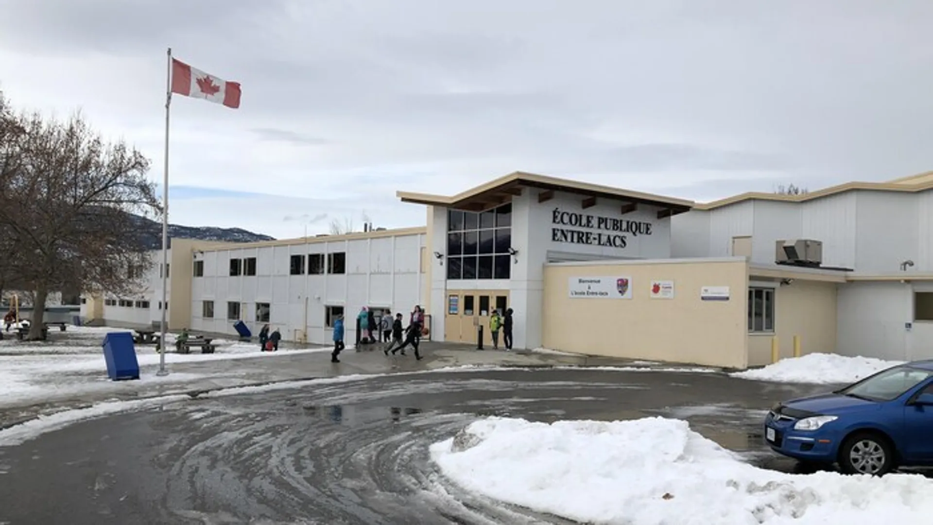 Una bandiera canadese sventola davanti a un paesaggio innevato nel terreno della École Entre-Lacs.