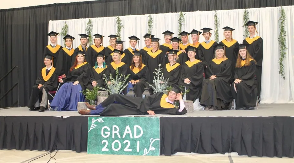 I diplomati della Thorsby Junior Senior High School posano con la toga da diploma davanti a uno striscione con la scritta Grad 2021.