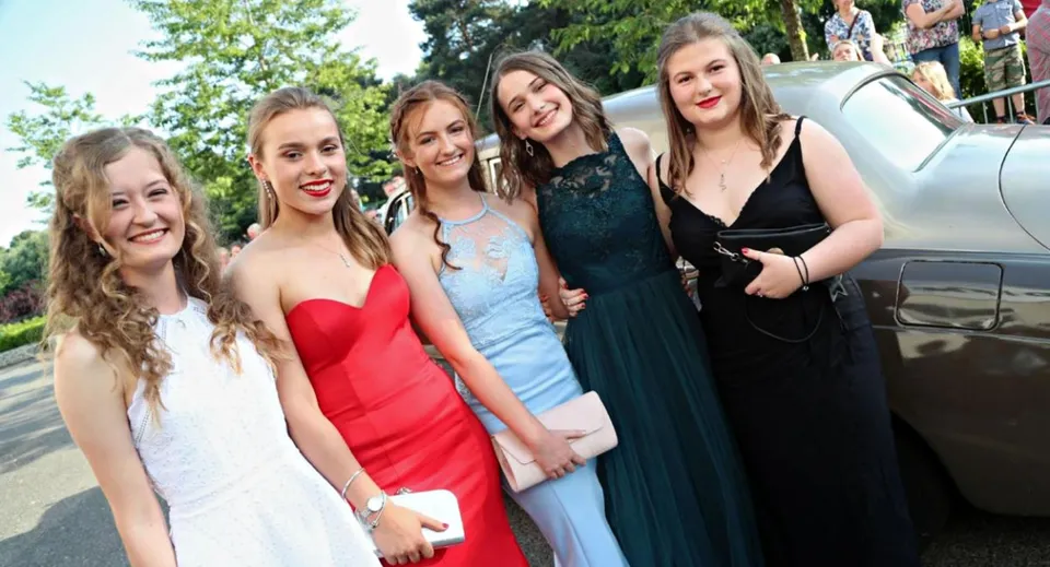 Un gruppo di studentesse della Presentation Secondary School (Tipperary) posa all'aperto davanti ad alberi e a un veicolo.