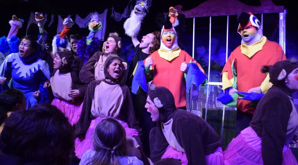 Gli studenti del Belmont City College mettono in scena uno spettacolo teatrale su un palco con un'illuminazione d'effetto.