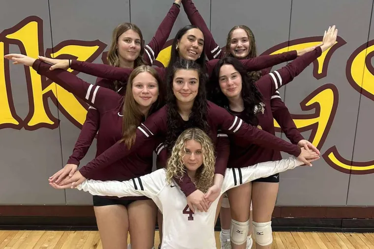 Grupo de jóvenes jugadoras de voleibol posando juntas en un pabellón deportivo