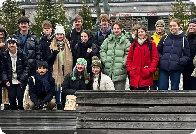Gruppo di studenti in abiti invernali in posa in una piazza cittadina