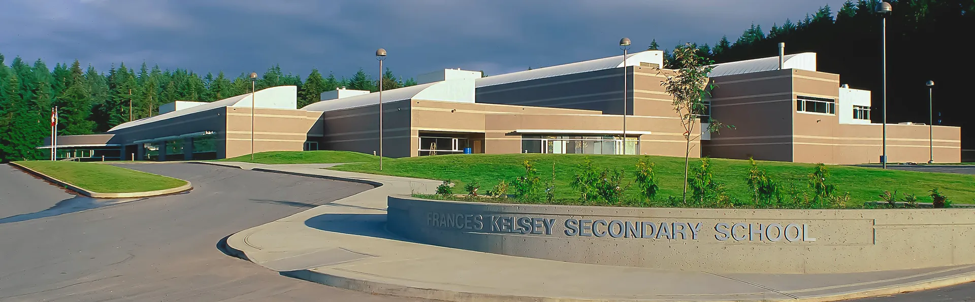 Si vede il moderno edificio scolastico della Frances Kelsey Secondary School con un'area d'ingresso ben curata.