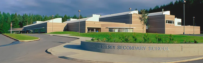 Si vede il moderno edificio scolastico della Frances Kelsey Secondary School con un'area d'ingresso ben curata.