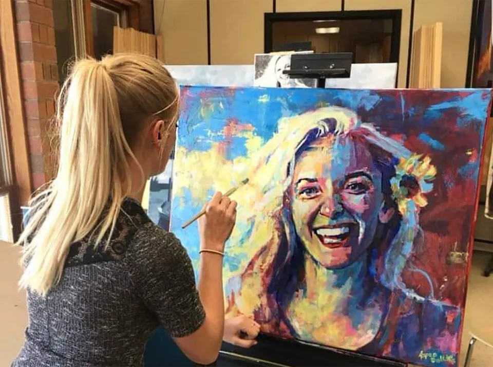 Una studentessa della Bonneville High School dipinge un ritratto variopinto su una tela durante la lezione d'arte.