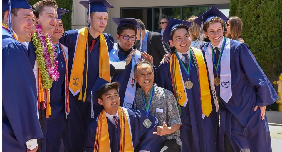 I diplomati della Pacifica Christian High School sono insieme in abito da cerimonia viola e oro durante la festa di diploma.