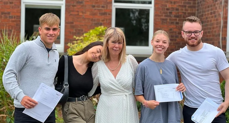 Quattro studenti della Read School si trovano davanti a un edificio in mattoni e mostrano dei certificati.