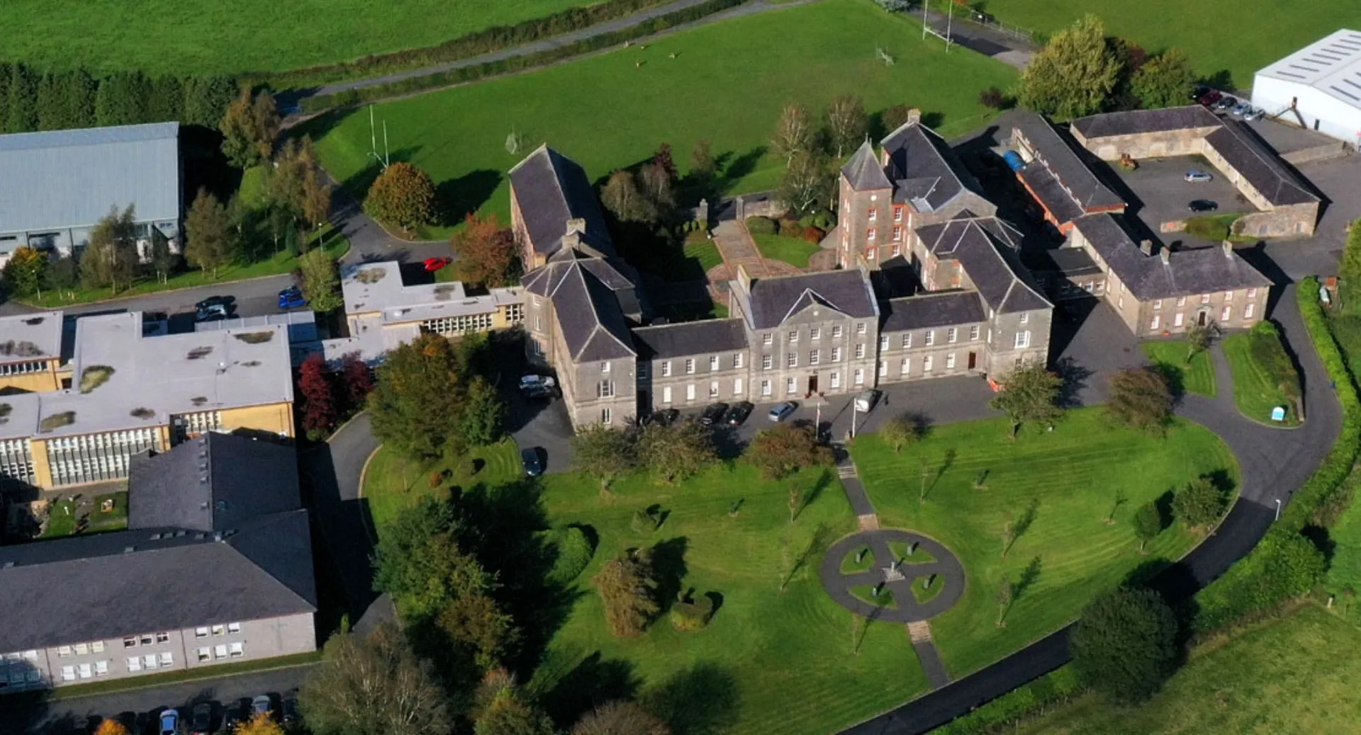 Un grande edificio storico simile a un castello sorge su una collina erbosa nel campus del St. Macartan's College.