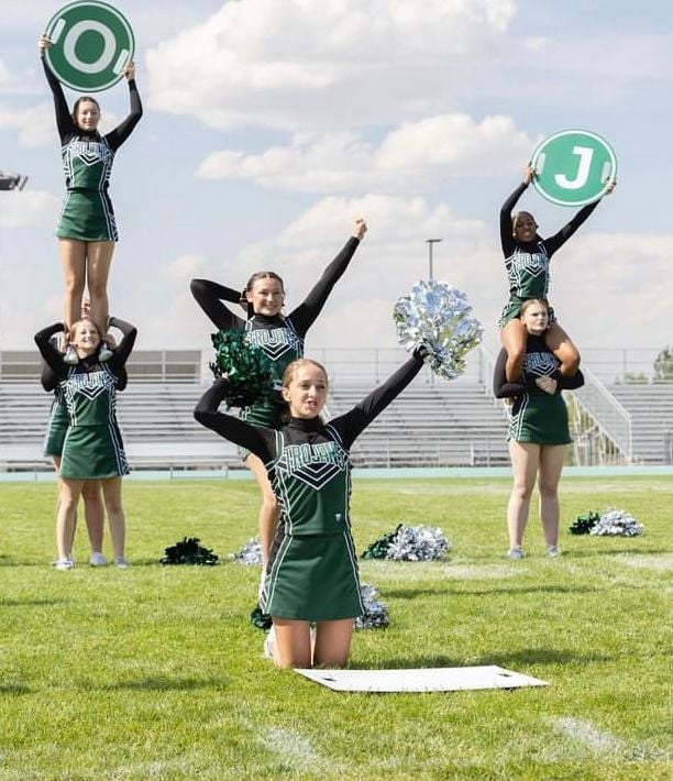 Squadra di cheerleader in divisa verde si esibisce sul campo sportivo di una high school americana