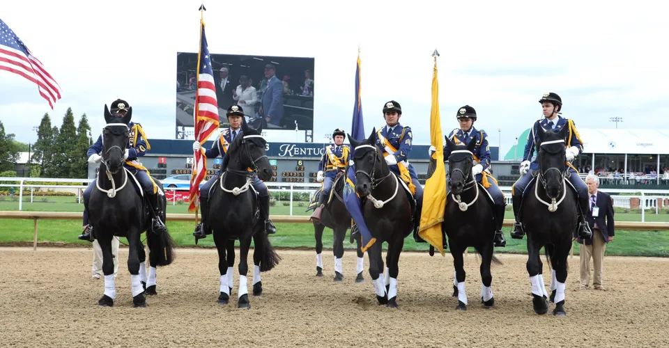 Un gruppo di cavalieri in uniforme su cavalli neri con bandiere si trova sulla pista della Indiana Private Highschool.