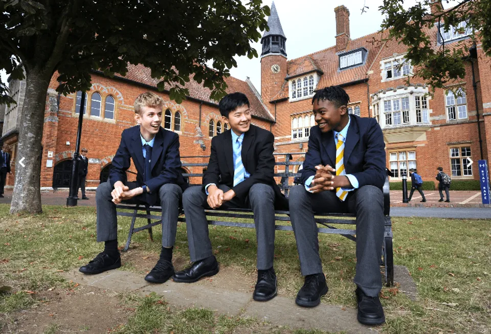 Tre studenti della Abingdon School siedono su panchine nel cortile interno tra edifici in mattoni.