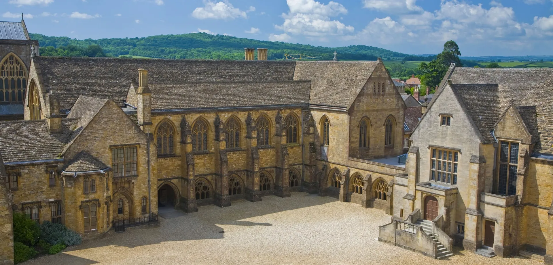 Una città medievale con una struttura simile a una cattedrale si vede davanti alle colline sotto un cielo nuvoloso.