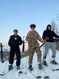 Tres estudiantes con esquís en una pista de nieve al atardecer