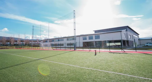 Struttura sportiva moderna con campo da tennis davanti all'edificio a più piani nel terreno della Ballinteer Community School.