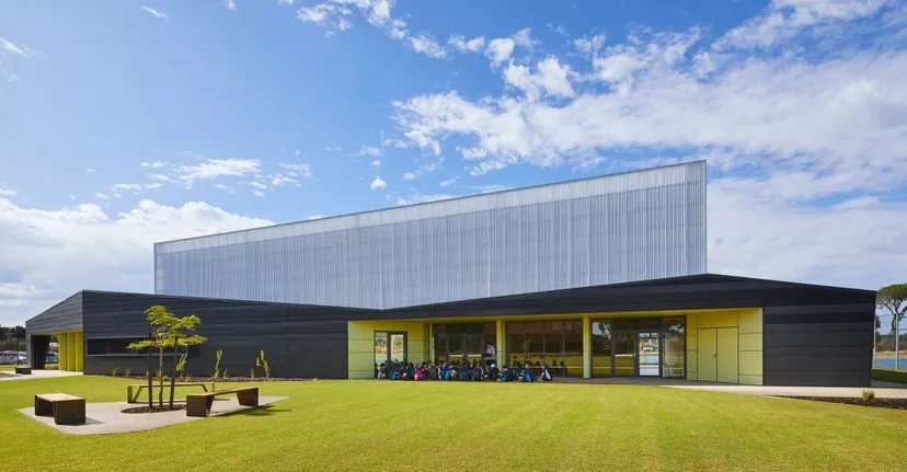 L'edificio moderno con facciata argentata nel campus del Southern River College si trova davanti a un cielo blu con nuvole bianche.
