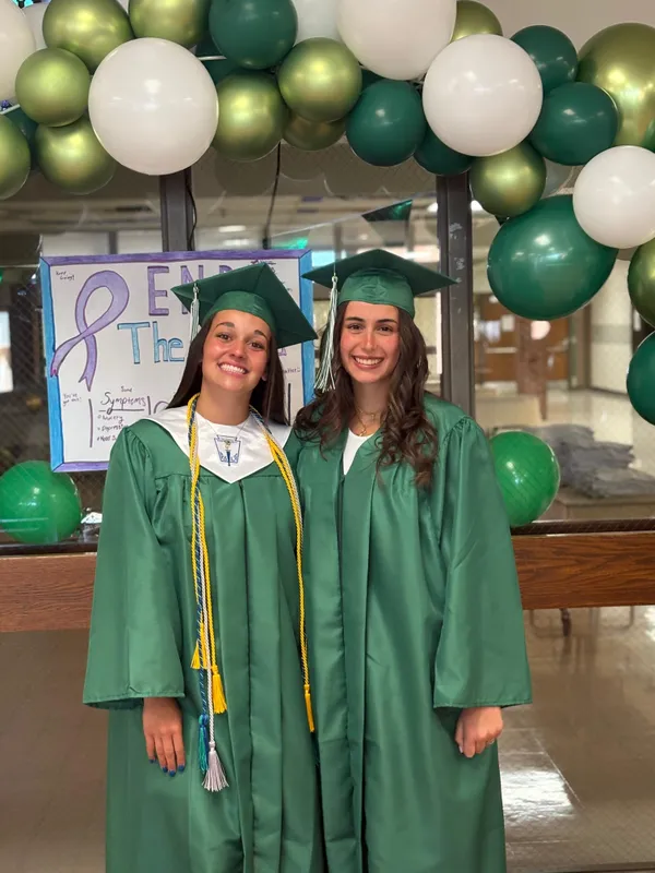 Due studentesse in toga e tocco verdi il giorno del diploma alla high school