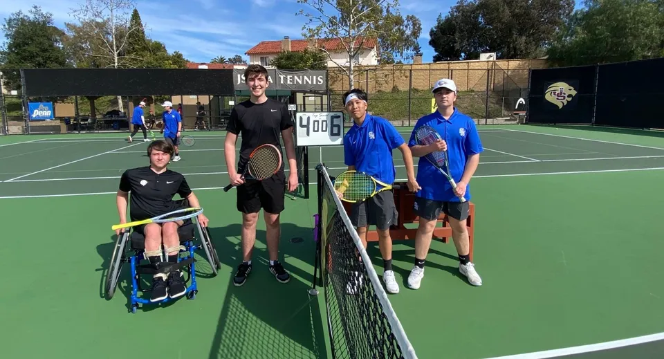 Studenti della Hackett High School si trovano sul campo da tennis davanti alla rete durante una sessione di allenamento all'aperto.