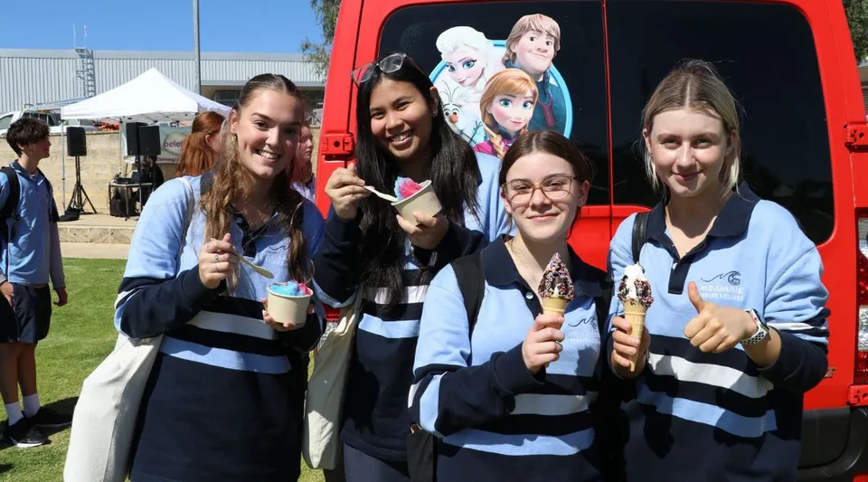 Un gruppo di studentesse del Mindarie Senior College posa davanti a un veicolo rosso con motivo Disney durante un evento all'aperto.