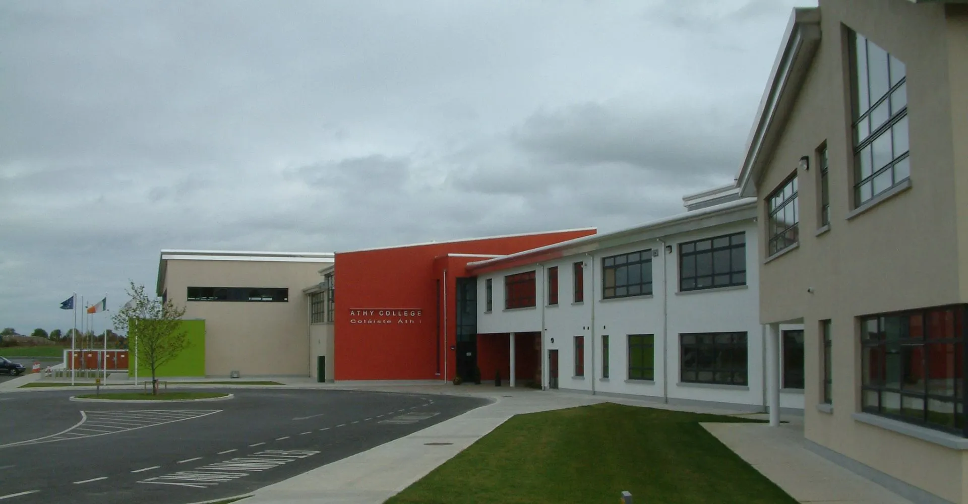 L'edificio moderno a più piani con parete d'accento rossa nel campus dell'Athy College è circondato da un'area pavimentata e da un prato.