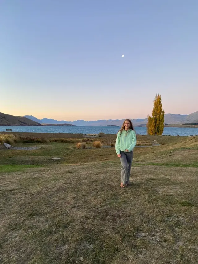 Studentessa che passeggia in riva a un lago al tramonto in Nuova Zelanda