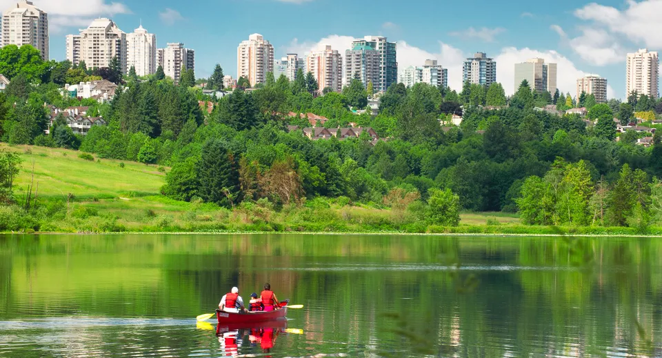 Due persone pagaiano in kayak su un lago sullo sfondo di edifici moderni nell'area della Burnaby South School.