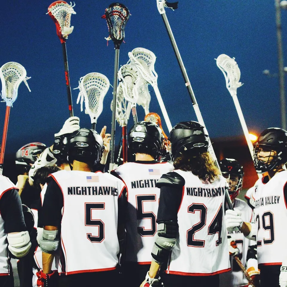 Un gruppo di giocatori di lacrosse della Murietta Valley High School indossa maglie bianche con la scritta NIGHTHAWKS sulla schiena.