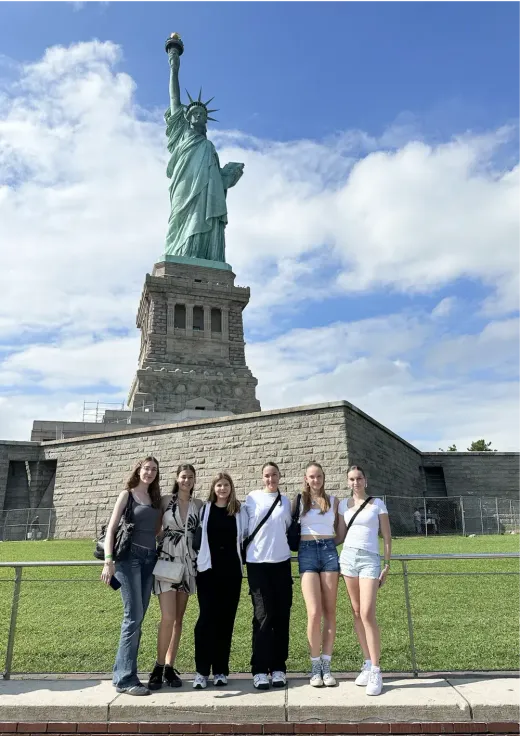 Gruppo di ragazze in posa davanti alla Statua della Libertà a New York