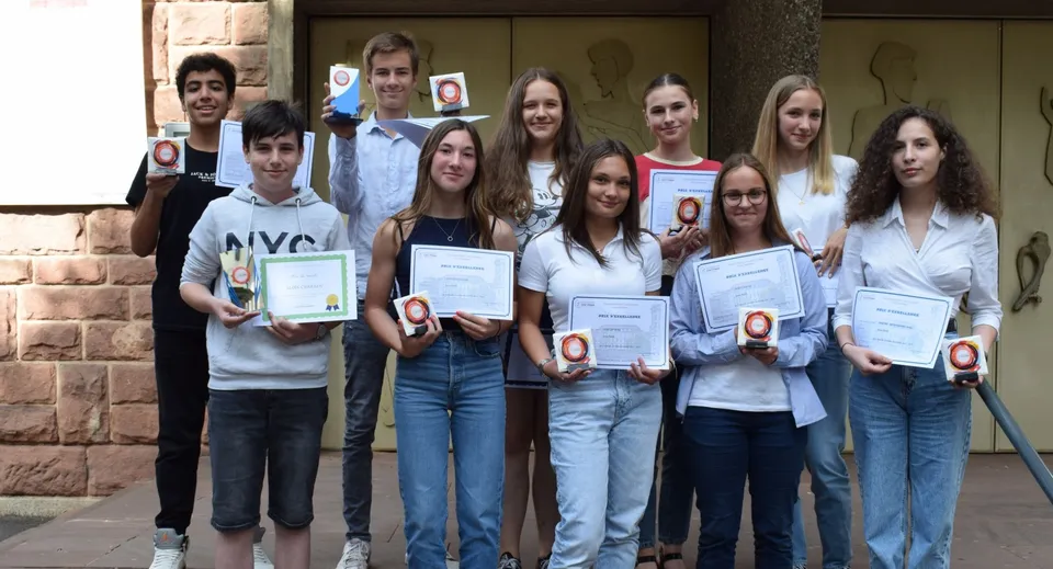 Studenti del Collège Episcopal Saint Étienne mostrano dei riconoscimenti davanti a un edificio in mattoni.
