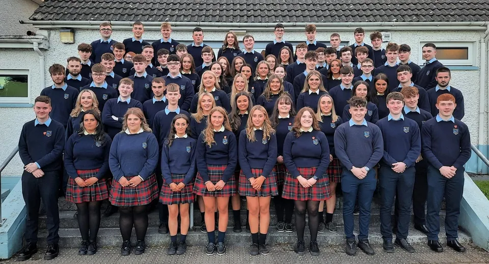 Un gruppo di studenti in uniforme scolastica davanti a un edificio con tetto in tegole nel campus della Scoil Mhuire (Strokestown).