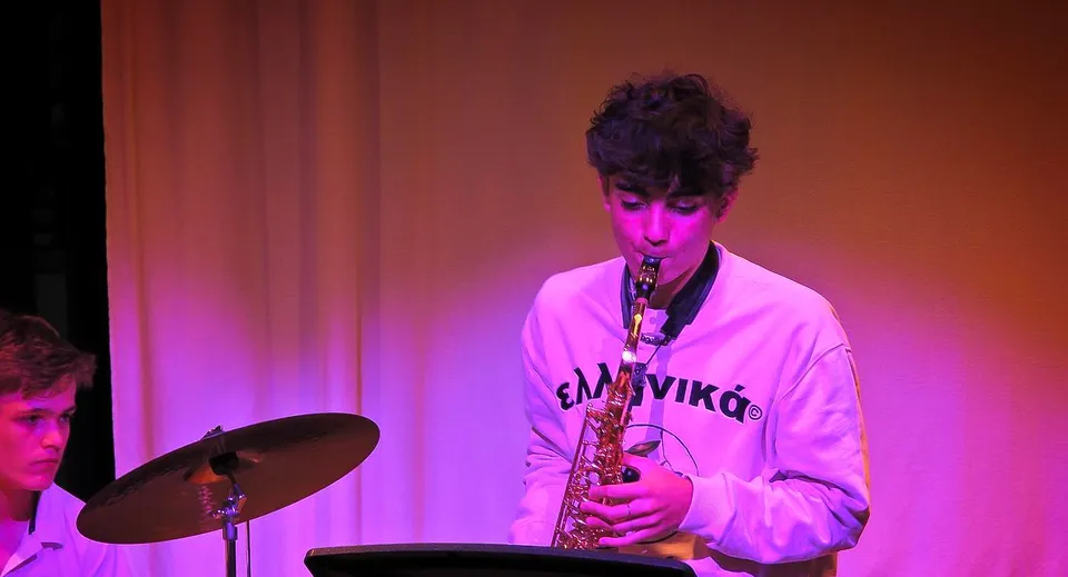 Una persona suona il sassofono sul palco davanti a luci colorate alla Kensington Park School.