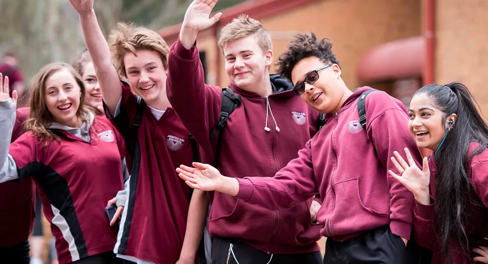Un gruppo di studenti della Aberfoyle Park High School è insieme all'aperto davanti a una parete di mattoni rossi.