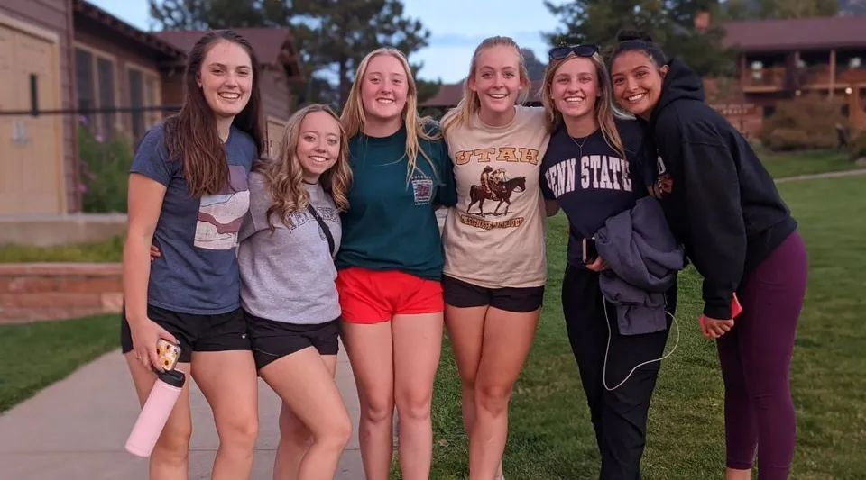 Un gruppo di studentesse si trova all'aperto su un prato con alberi sullo sfondo, nel campus della Pacific Lutheran High School.