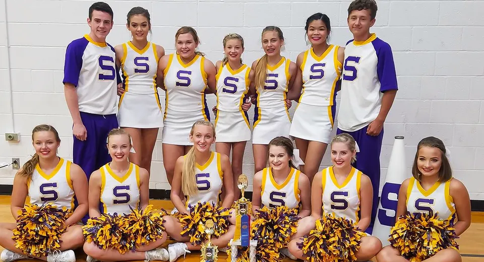 Un gruppo di cheerleader della Scottsburg High School posa davanti a una parete bianca.