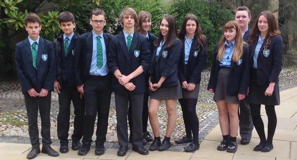 Un gruppo di studenti e studentesse si trova nel giardino sul terreno della Seaford Head School.