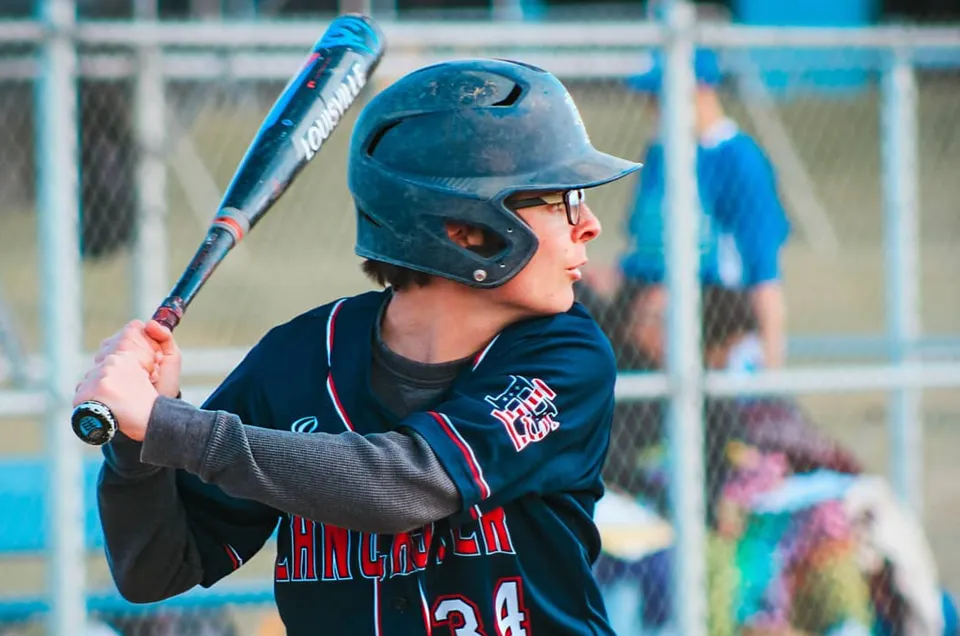 Un giovane giocatore di baseball si trova nella gabbia di battuta nell'area sportiva della Littlerock High School.